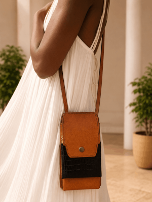 Black female model wearing a white dress with a handmade genuine leather mini crossbody phone bag in tan and black by NUA Bags.